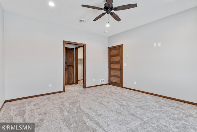 unfurnished bedroom featuring ceiling fan, a walk in closet, and light carpet