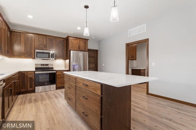 kitchen with light hardwood / wood-style floors, stainless steel appliances, pendant lighting, light stone counters, and a center island