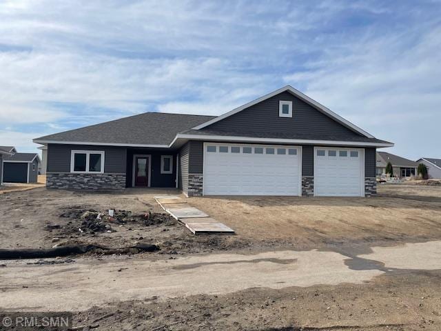 view of front of house featuring a garage, stone siding, and driveway