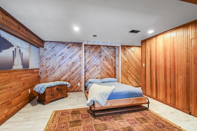 bedroom with wooden walls and a textured ceiling