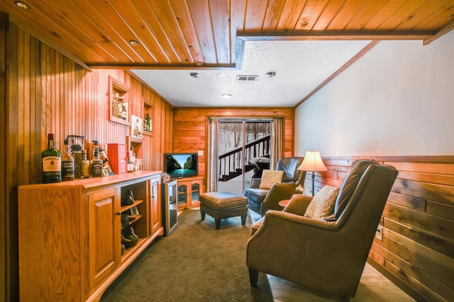 living area with bar, wooden walls, ornamental molding, and dark colored carpet