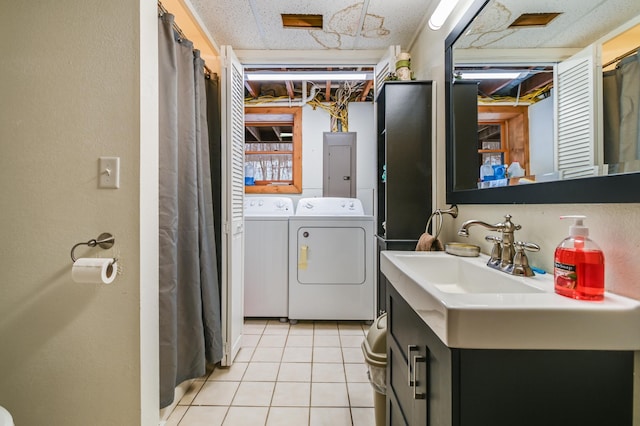 washroom featuring light tile patterned floors, electric panel, sink, and washing machine and clothes dryer