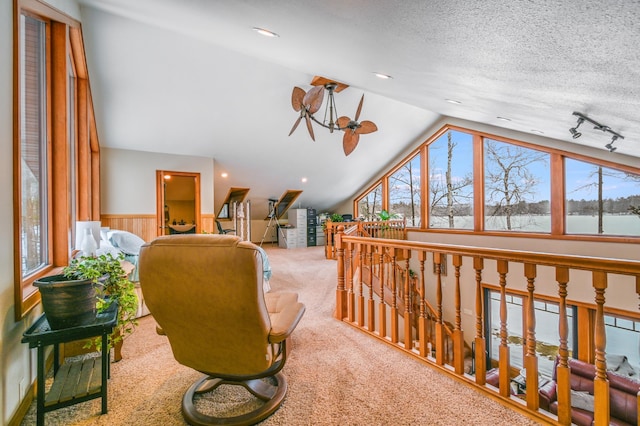 sitting room with vaulted ceiling, carpet, a textured ceiling, and wooden walls