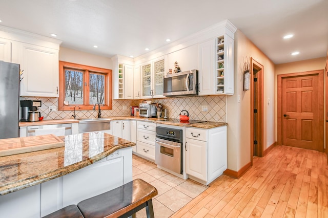 kitchen featuring white cabinetry, sink, light stone counters, and stainless steel appliances