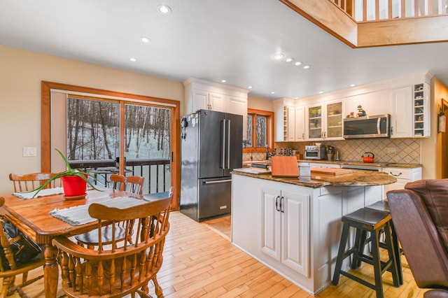 kitchen featuring light hardwood / wood-style floors, a center island, white cabinets, and black fridge