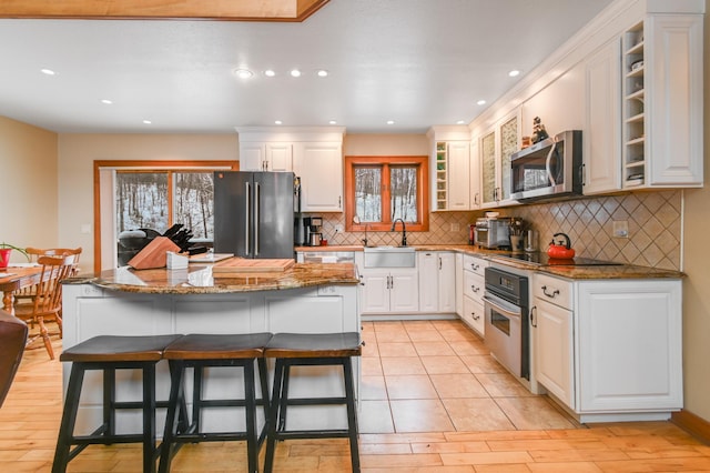 kitchen featuring sink, a kitchen island, stainless steel appliances, white cabinets, and a kitchen bar