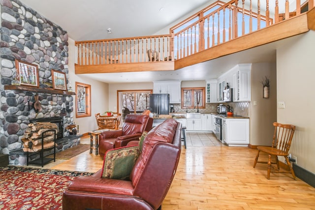 living room featuring a towering ceiling, sink, a fireplace, and light wood-type flooring