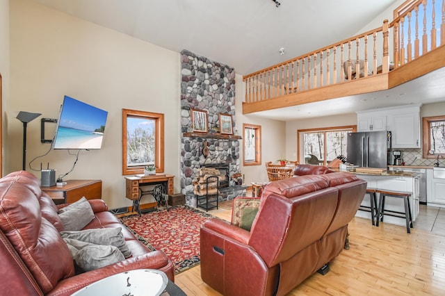 living room featuring a towering ceiling, a fireplace, and light wood-type flooring