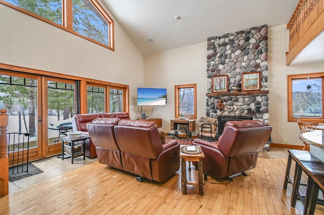 living room featuring french doors, a fireplace, light hardwood / wood-style floors, and high vaulted ceiling