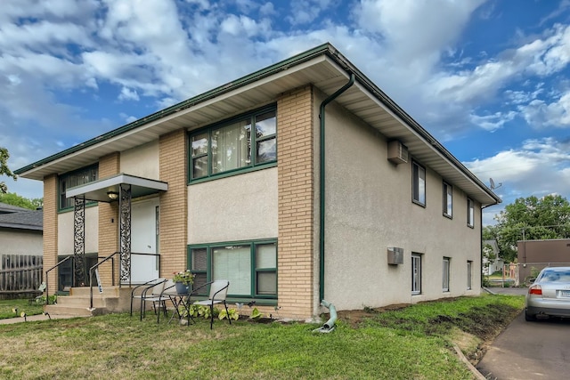 view of side of property featuring a wall unit AC, brick siding, and stucco siding