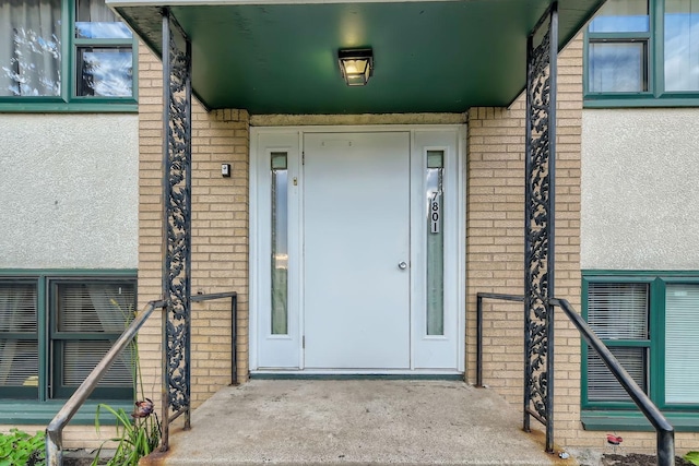 doorway to property with brick siding and stucco siding