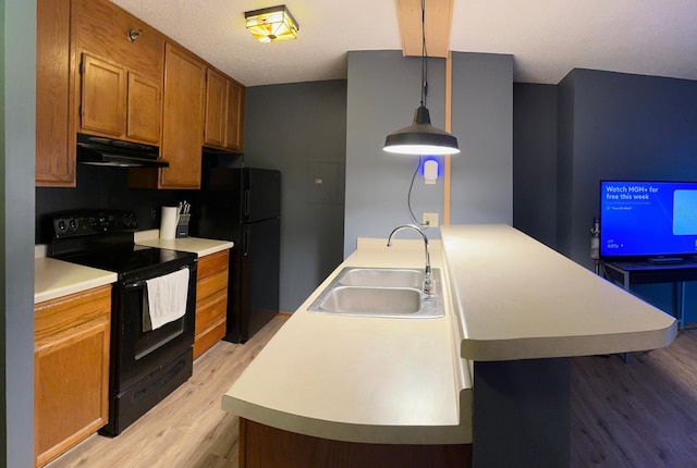 kitchen featuring black appliances, a kitchen bar, light hardwood / wood-style floors, sink, and hanging light fixtures