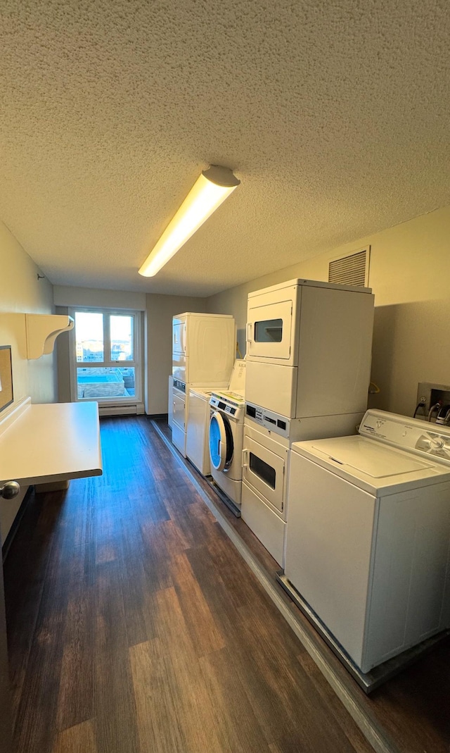 clothes washing area with dark wood-type flooring, stacked washer / dryer, a textured ceiling, and independent washer and dryer