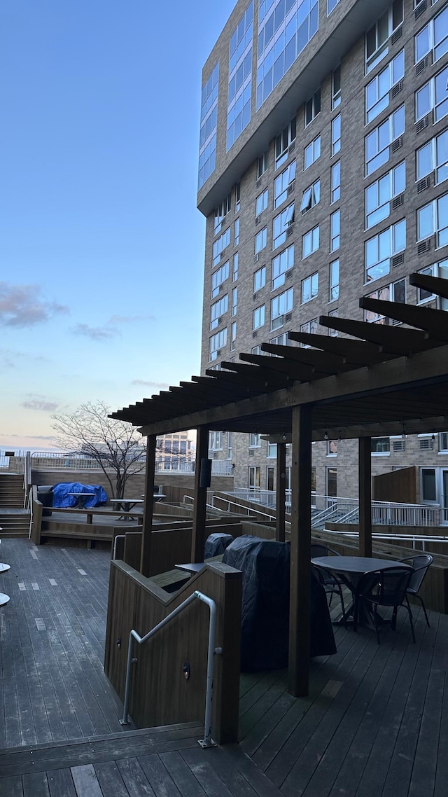 deck at dusk featuring a pergola