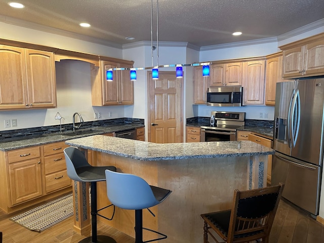 kitchen featuring a center island, sink, decorative light fixtures, a breakfast bar, and stainless steel appliances