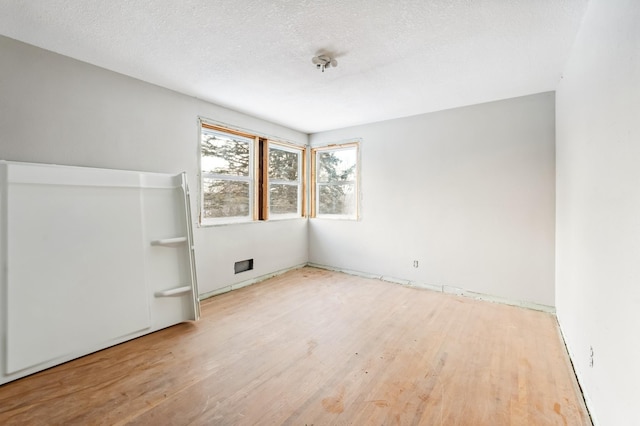 spare room featuring wood-type flooring and a textured ceiling