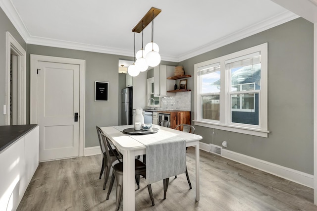 dining room featuring light wood-type flooring, ornamental molding, and sink