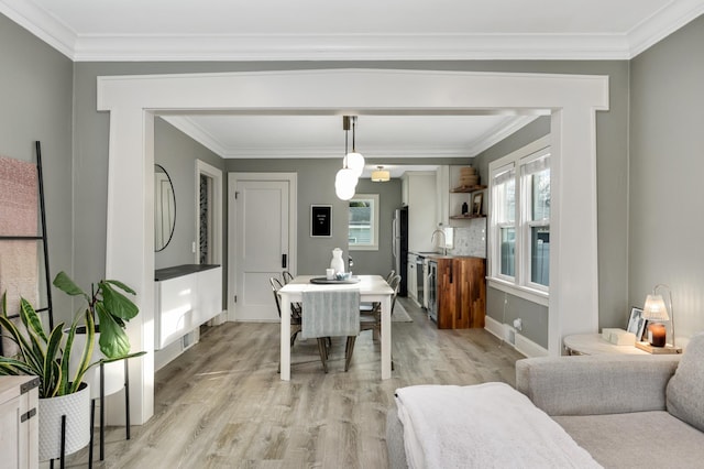 dining area featuring sink, ornamental molding, and light wood-type flooring