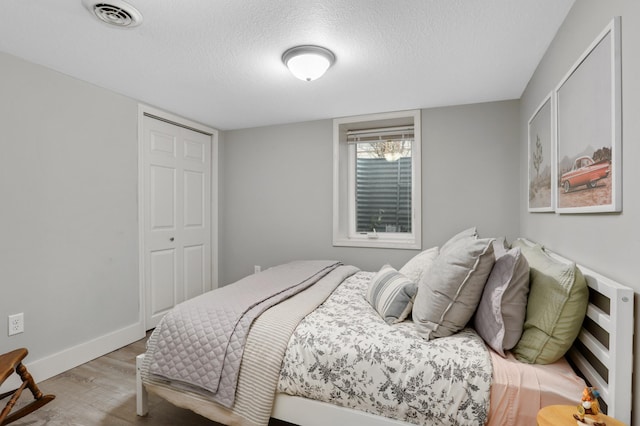 bedroom with a textured ceiling, a closet, and light hardwood / wood-style flooring