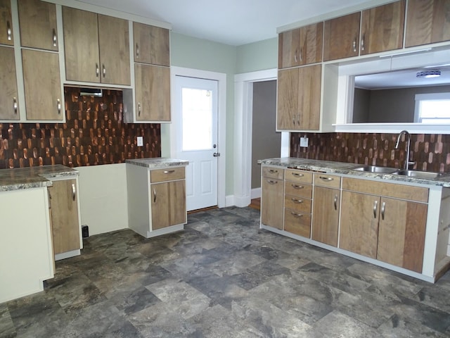 kitchen with backsplash, stone finish flooring, and a sink