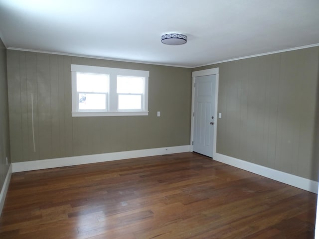 spare room featuring wood finished floors, baseboards, and ornamental molding