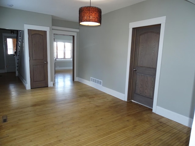 unfurnished room featuring hardwood / wood-style flooring, baseboards, and visible vents