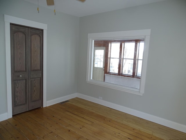 unfurnished bedroom featuring visible vents, baseboards, a closet, and hardwood / wood-style floors