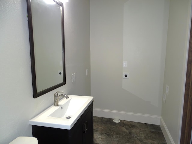 bathroom with toilet, vanity, and baseboards