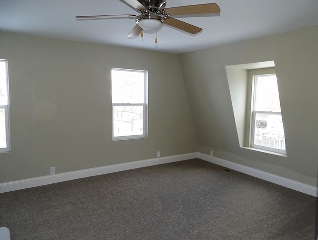 empty room featuring ceiling fan, baseboards, and dark colored carpet