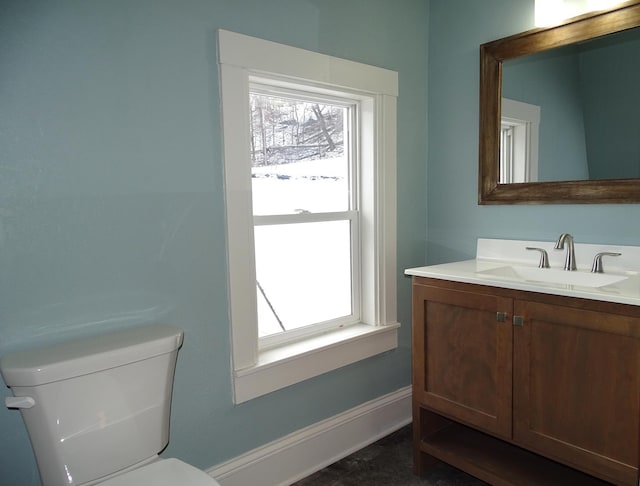 bathroom with vanity, toilet, a healthy amount of sunlight, and baseboards