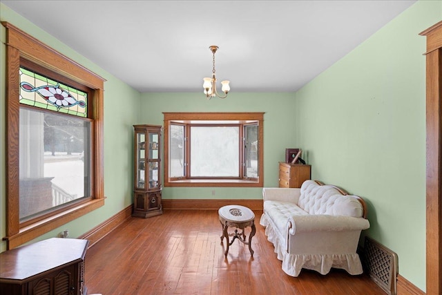 sitting room with hardwood / wood-style flooring and an inviting chandelier