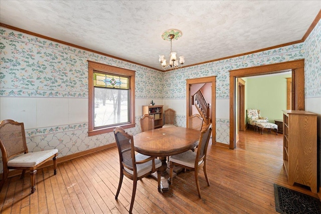 dining room featuring a textured ceiling, an inviting chandelier, crown molding, and wood-type flooring