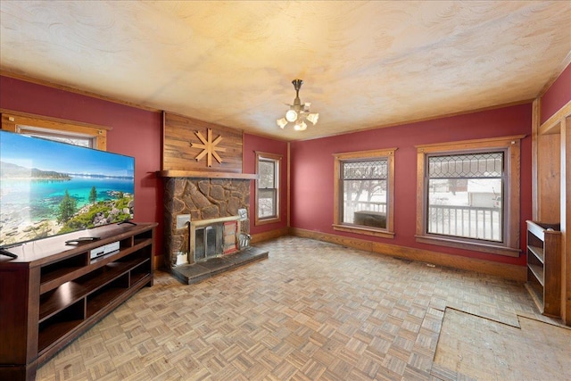 unfurnished living room featuring light parquet floors, a textured ceiling, a notable chandelier, and a stone fireplace