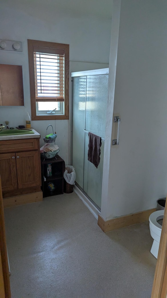 bathroom with a shower with shower door, vanity, and toilet