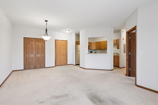 unfurnished living room featuring baseboards and light colored carpet