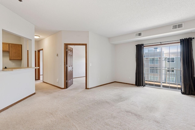 spare room with a textured ceiling, baseboards, visible vents, and light carpet