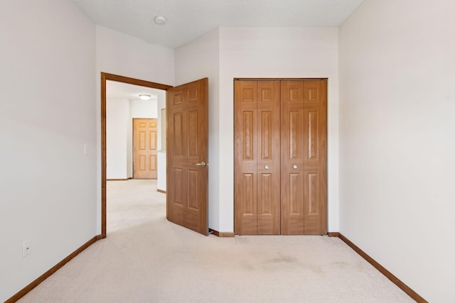 unfurnished bedroom featuring carpet flooring, baseboards, and a closet