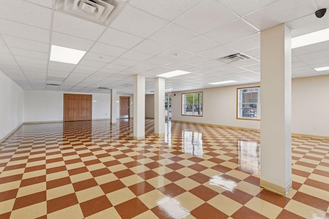 basement featuring tile patterned floors, baseboards, a drop ceiling, and visible vents