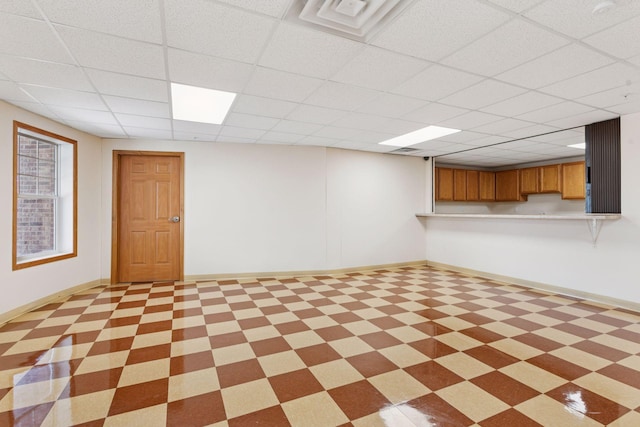 basement featuring baseboards and a paneled ceiling