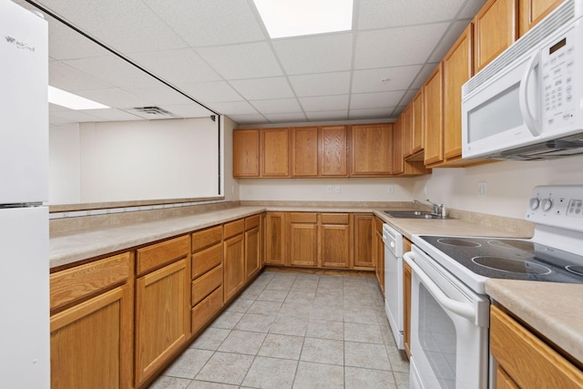 kitchen featuring a sink, light countertops, white appliances, and a paneled ceiling