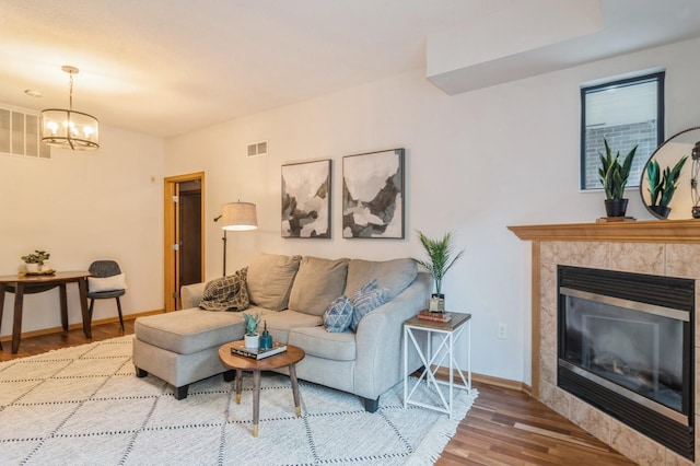 living room featuring a fireplace, wood finished floors, visible vents, and baseboards