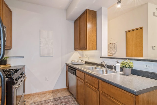 kitchen with appliances with stainless steel finishes, brown cabinetry, a sink, and baseboards