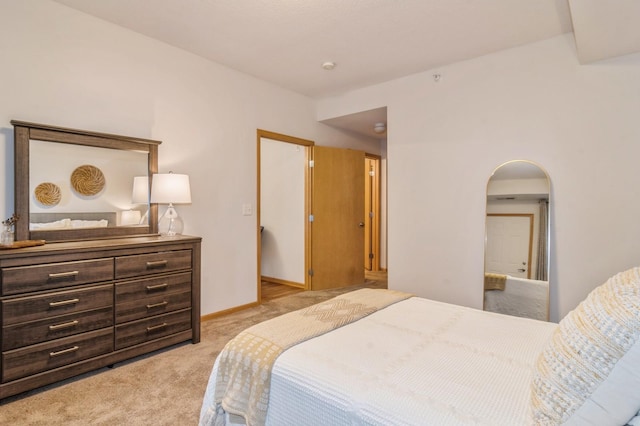 bedroom with baseboards, arched walkways, and light colored carpet