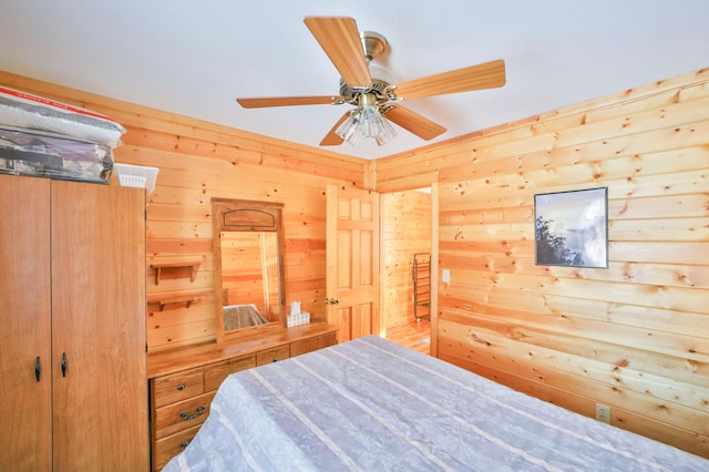 bedroom with ceiling fan and wood walls