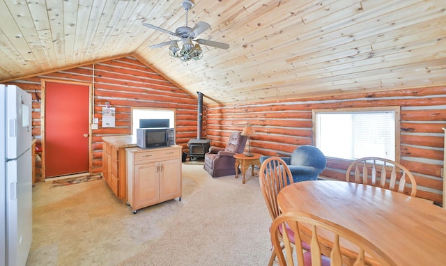 dining room with lofted ceiling, a wood stove, log walls, ceiling fan, and wooden ceiling