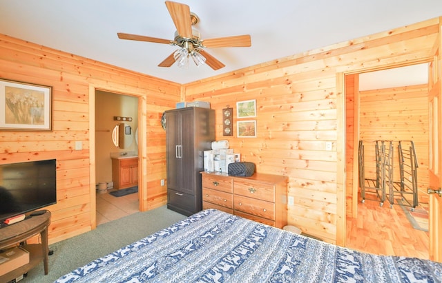 bedroom featuring connected bathroom, ceiling fan, and wood walls