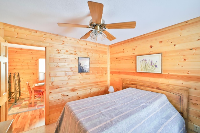 bedroom with ceiling fan and wooden walls