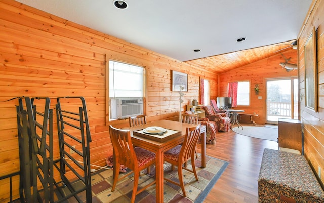 dining space with cooling unit, wood-type flooring, vaulted ceiling, and wood walls