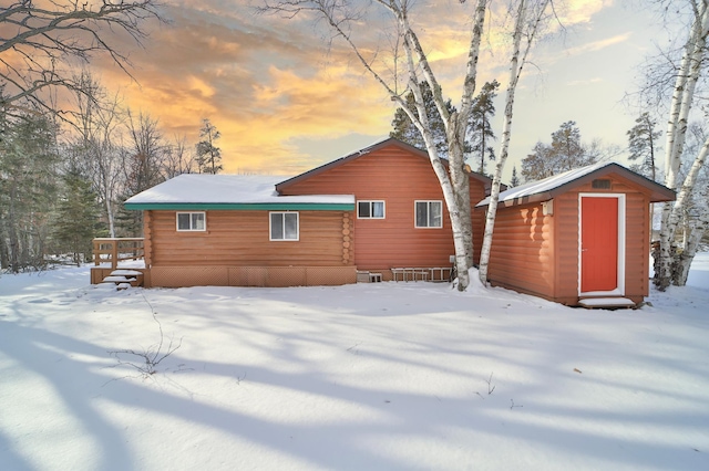 snow covered back of property with a shed