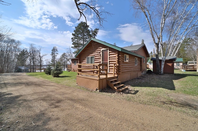 view of side of property with log exterior, a yard, and a deck